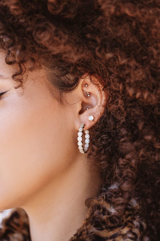 Stylish close-up side profile featuring intricate earrings and curly hair.